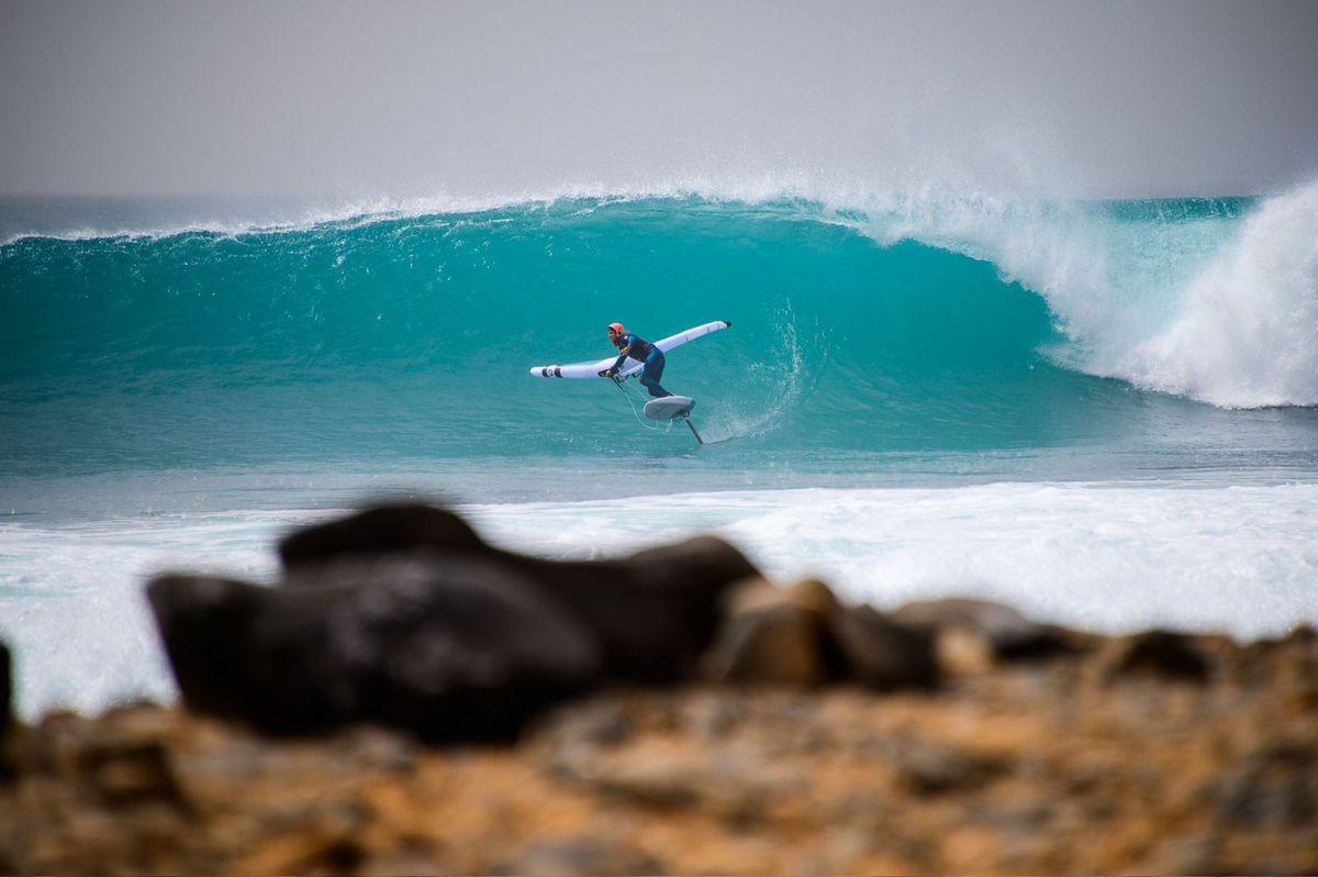 Elena Moreno wing foiling inside a barrelling wave with her wing flagged out
