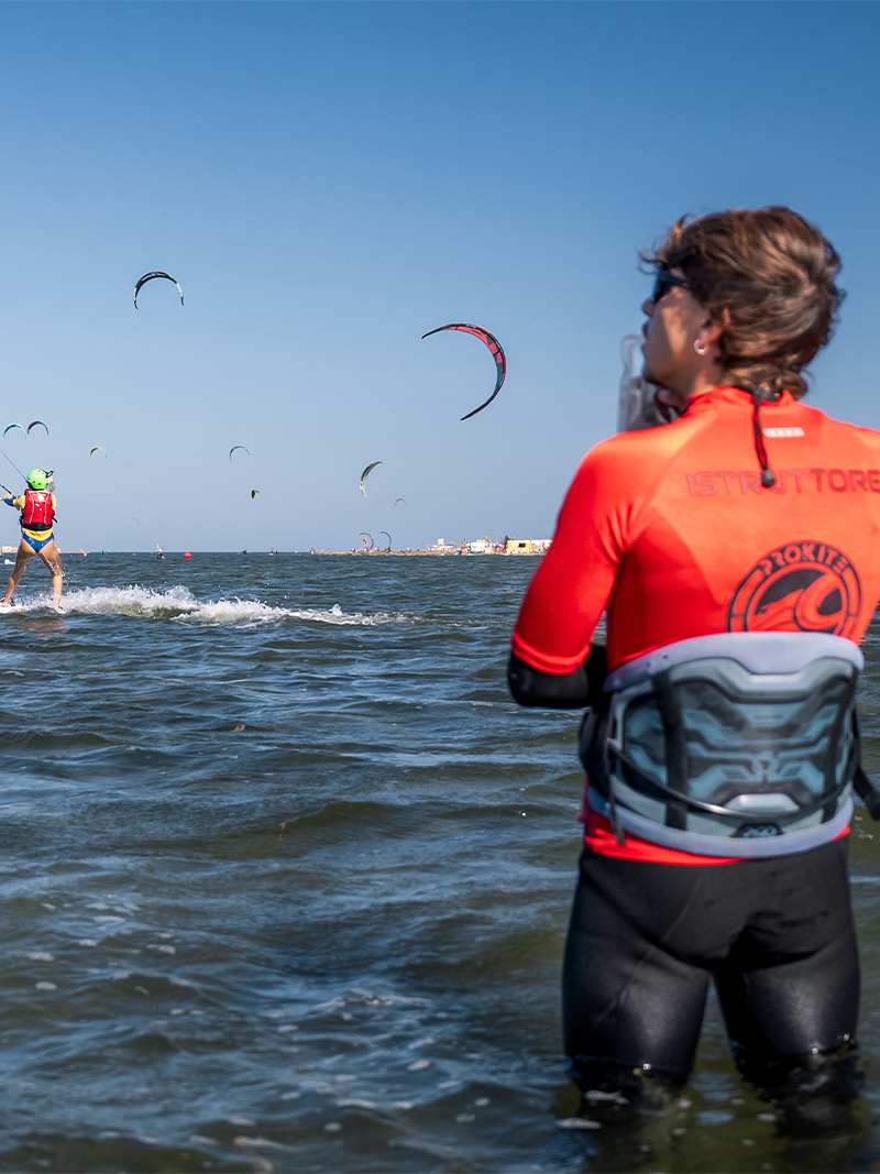Kitesurfing instructor supervising beginner students practicing on the water during a lesson.